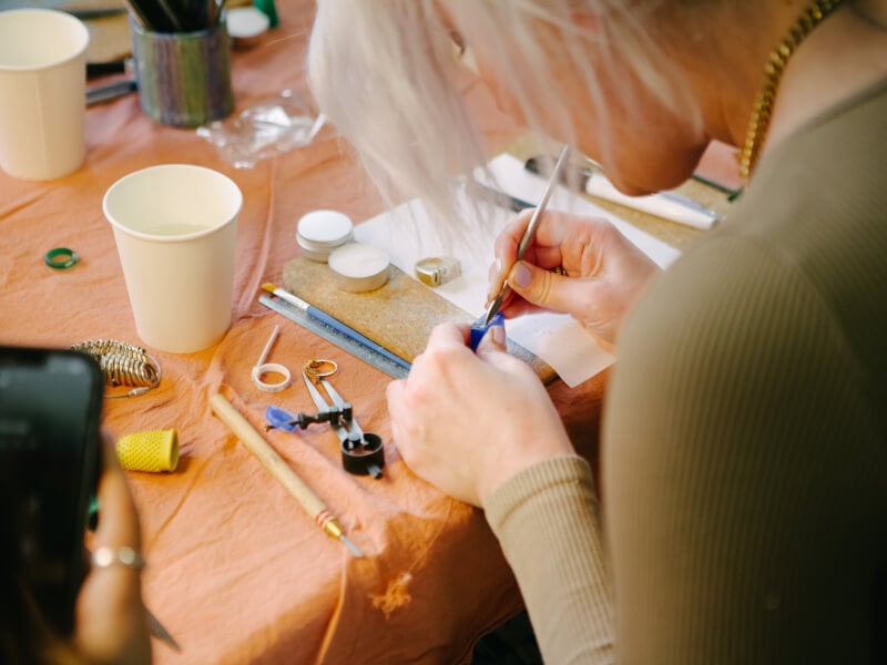 A close up shot of a woman carving a jewellery mould from blue wax